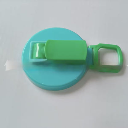Turquoise and green plastic lid with a clip on a white background