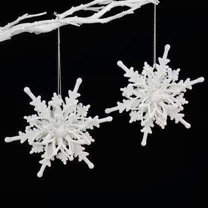 Two white snowflake-shaped ornaments hanging from a branch against a black background
