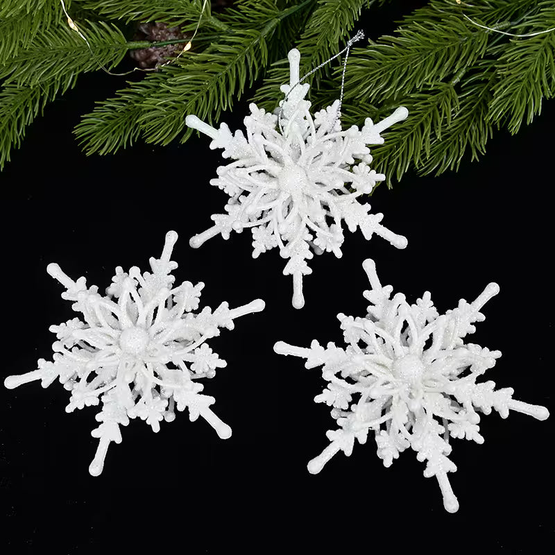 White snowflake ornaments on a black background with greenery.