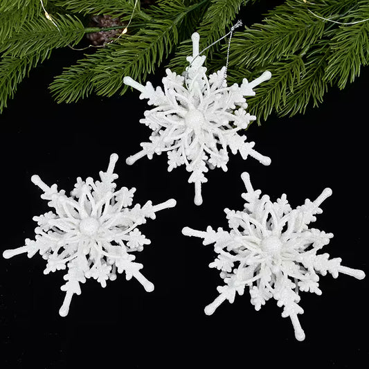 White snowflake ornaments on a black background with greenery.