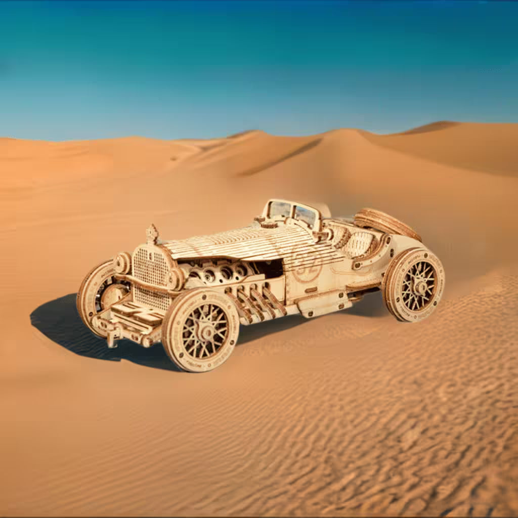 Wooden model of a vintage car on sand dunes with clear blue sky