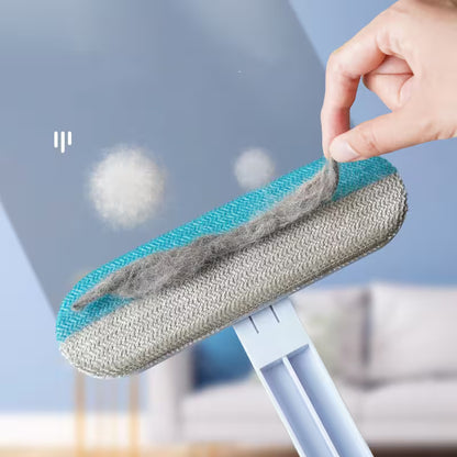 Hand holding a cleaning tool with a gray and blue head, likely for window cleaning, against a blurred indoor background.