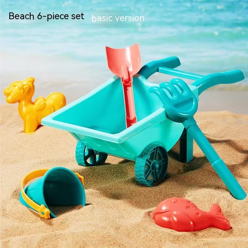 Colorful beach toy set with a wheelbarrow, shovel, and other tools on sand with ocean background.