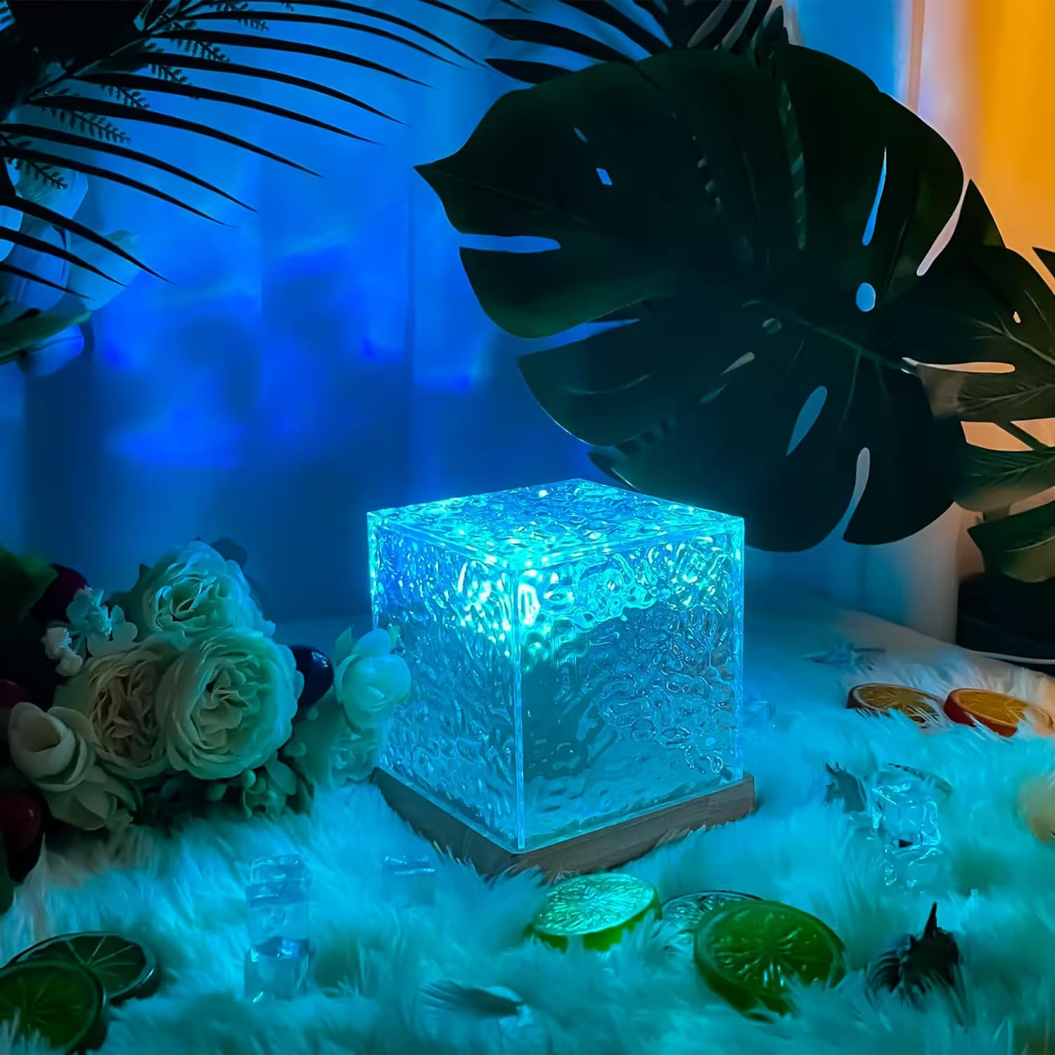 Decorative crystal cube with blue light on a fluffy surface with flowers and leaves.