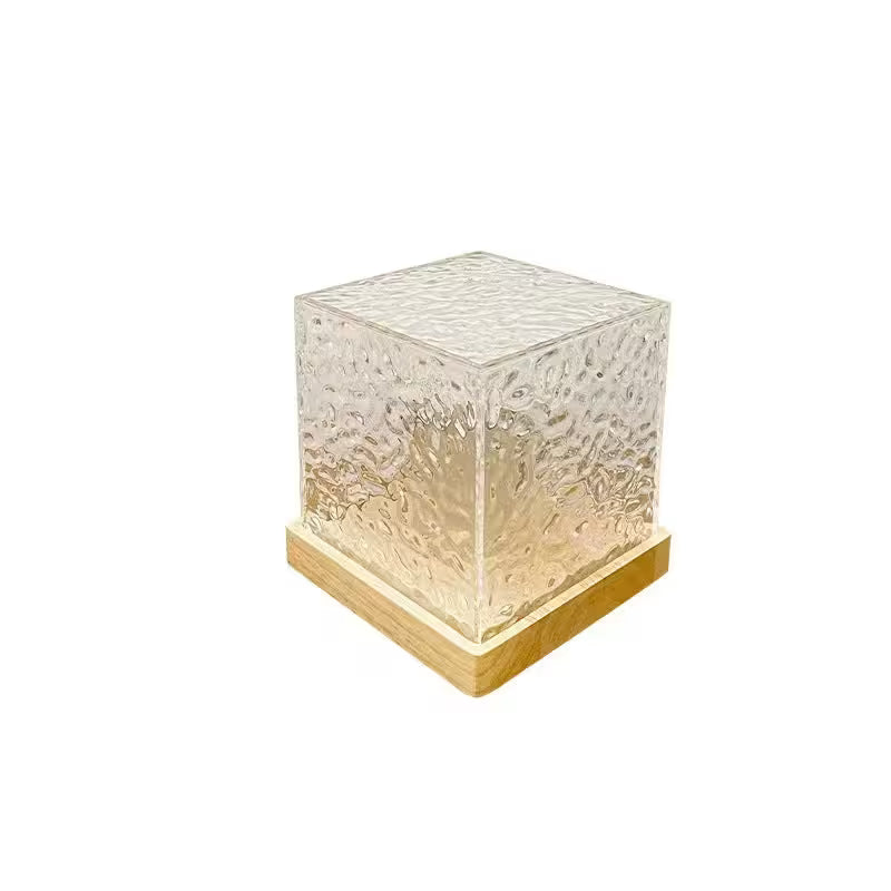 Cube-shaped lamp with textured glass and wooden base on a white background