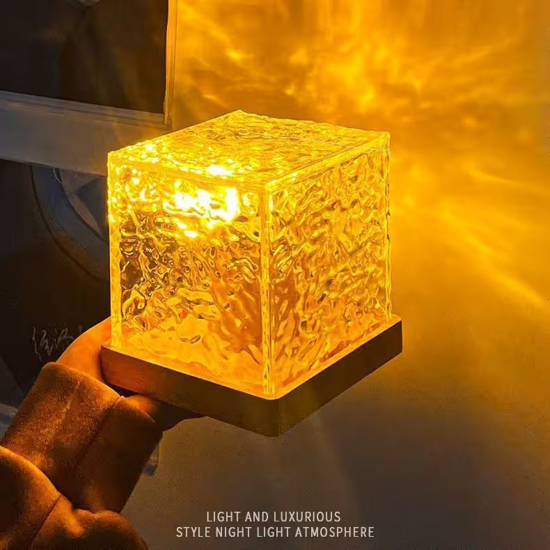 Glass cube night light emitting a warm glow, held by a hand.
