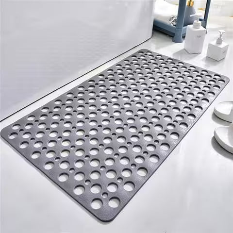 Gray perforated mat on a bathroom floor with cleaning supplies in the background