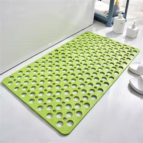 Green perforated mat on a bathroom floor with white bottles in the background