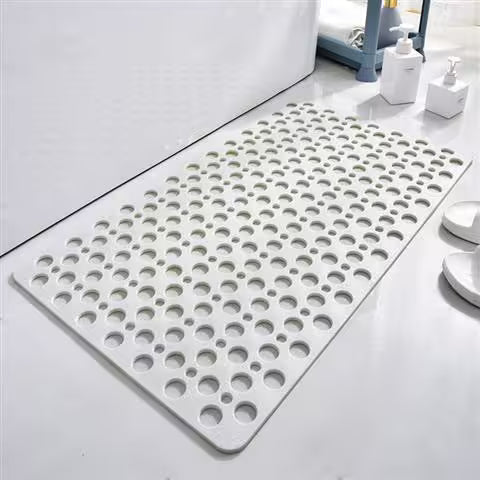 Gray bath mat with circular holes on a bathroom floor