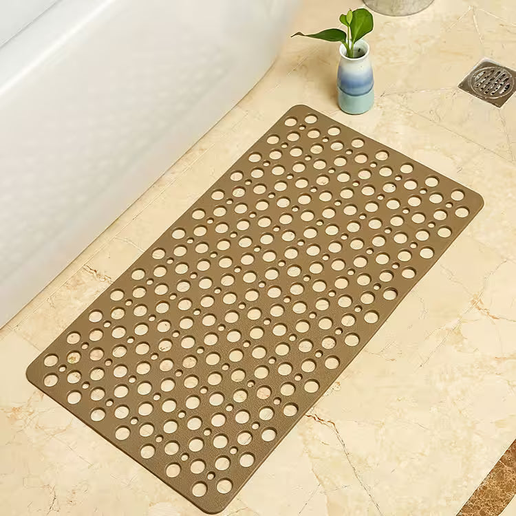 Brown bath mat with circular holes on a bathroom floor