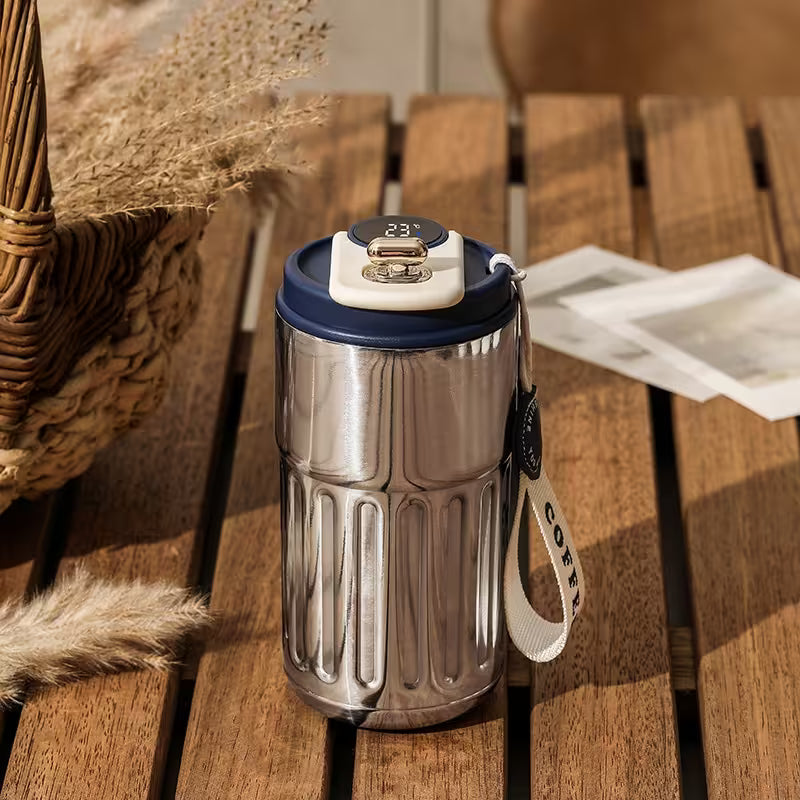 Silver tumbler with a blue lid on a wooden surface