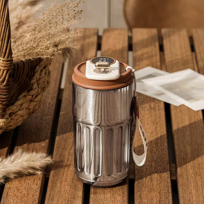 Silver insulated mug with brown lid on a wooden surface