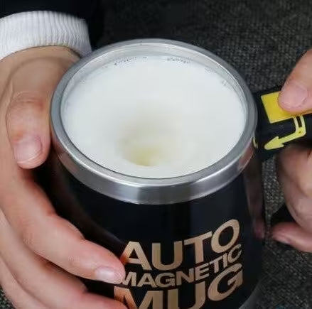 Person holding a black mug with 'Auto Magnetic Mug' text, using a tool to open it.