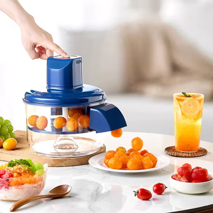 Fruit juicer with oranges, a glass of juice, and fruit salad on a table.