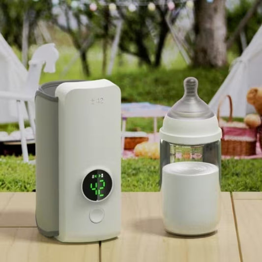 White electronic device with digital display next to a baby bottle on a wooden surface outdoors.