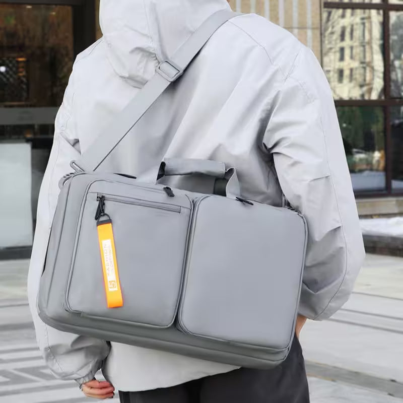 Person carrying a gray backpack with an orange tag outdoors.