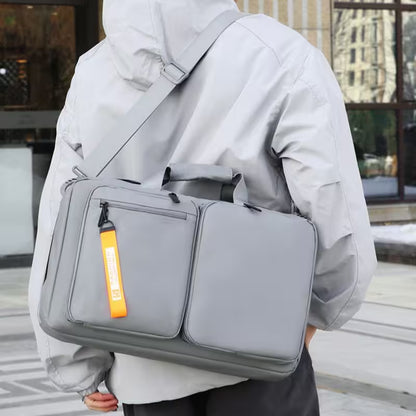 Person carrying a gray backpack with an orange tag outdoors.
