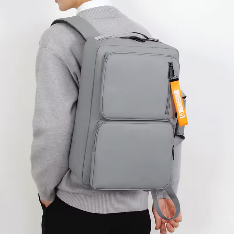 Person wearing a gray backpack with an orange tag on a white background