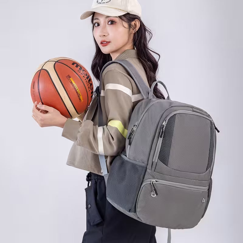 Person holding a basketball and wearing a gray backpack on a white background