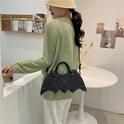 Woman holding a black bat-shaped handbag in an indoor setting