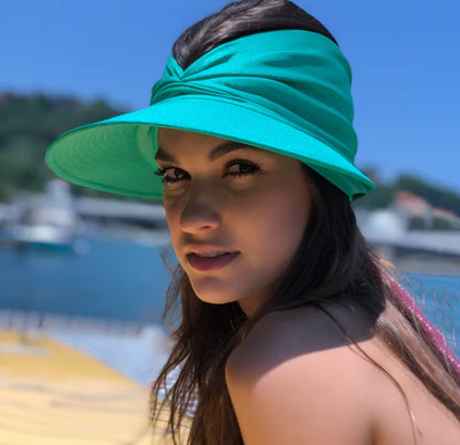 Woman wearing a turquoise visor with a blurred beach background
