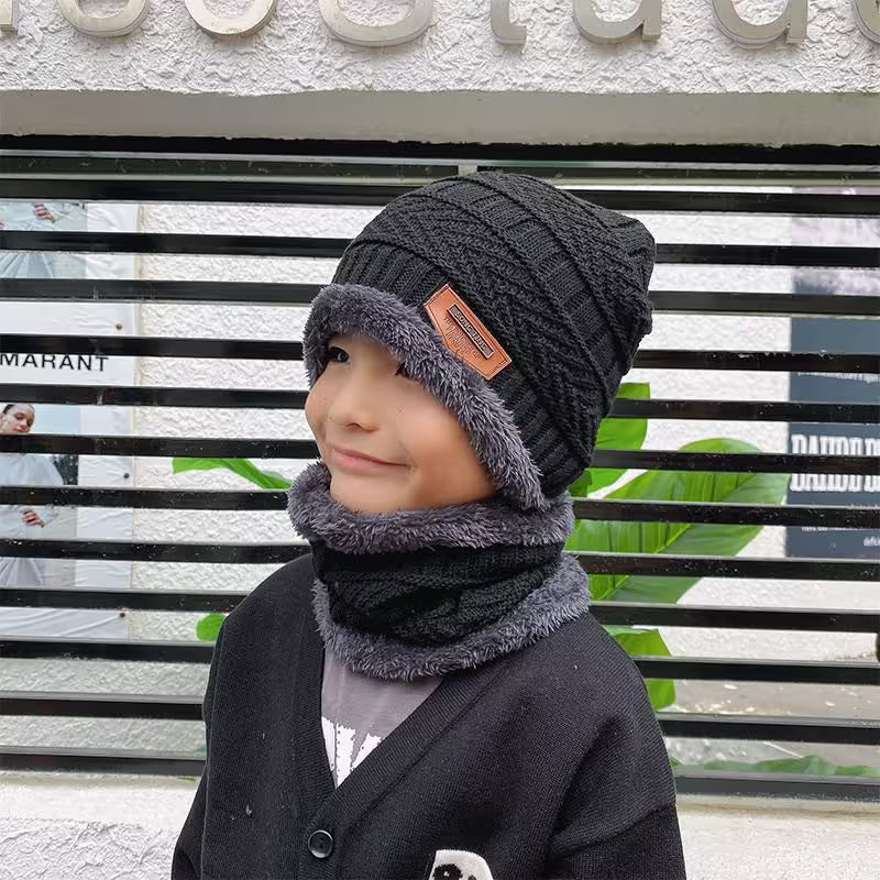 Child wearing a dark gray knit hat and scarf in front of a store with visible branding.