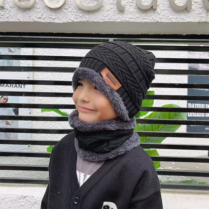 Child wearing a dark gray knit hat and scarf in front of a store with visible branding.