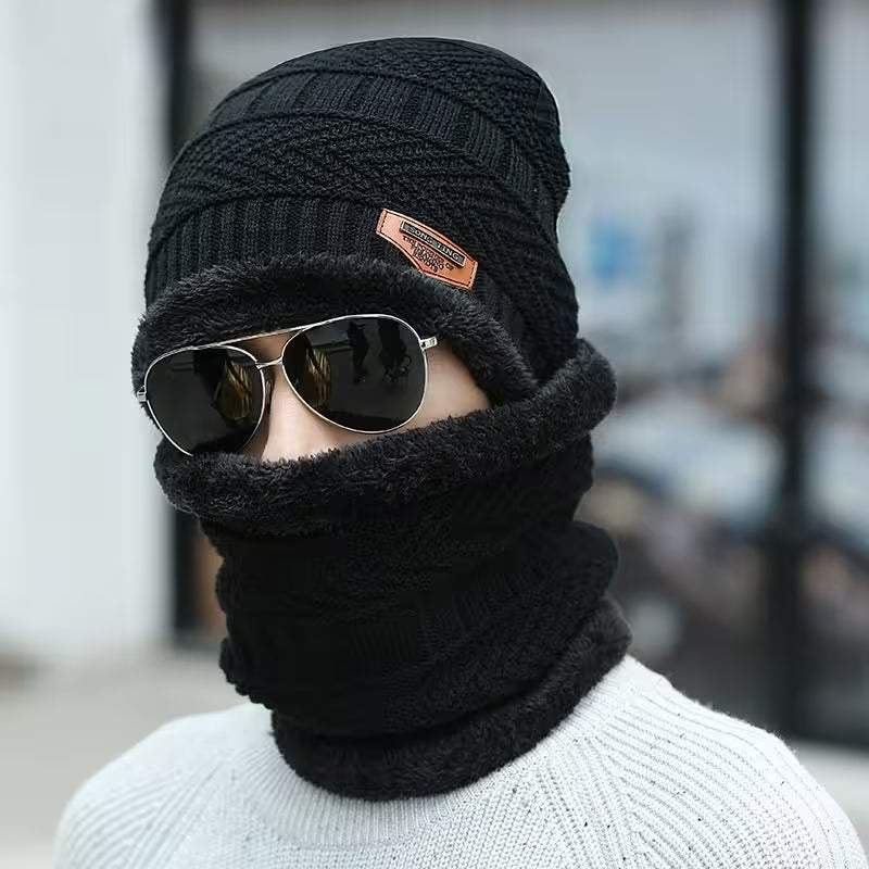 Person wearing a black knit beanie and scarf with sunglasses on a blurred background
