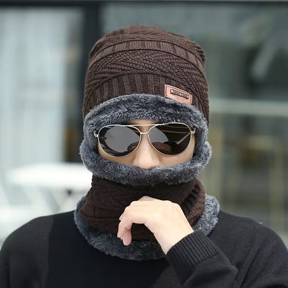 Person wearing a brown knitted beanie and gray scarf with sunglasses on a blurred background