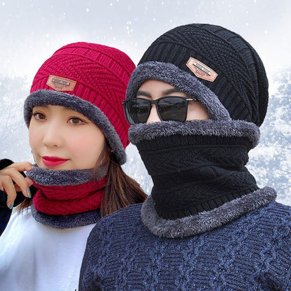 Two people wearing knitted hats and scarves with a snowy background