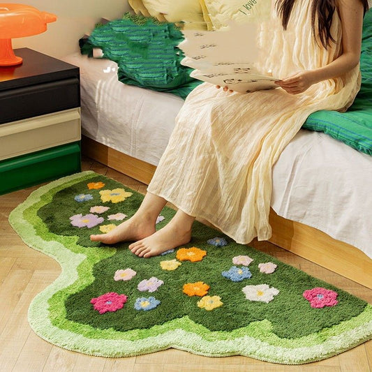 Person sitting on a bed with a floral-patterned rug on the floor.