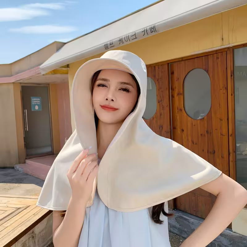 Woman wearing a beige hooded towel outdoors with a building in the background
