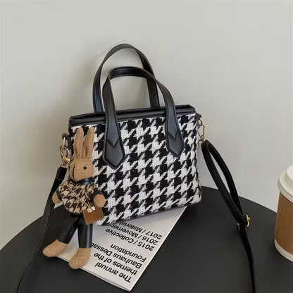 Houndstooth pattern handbag with bunny keychain on a black surface