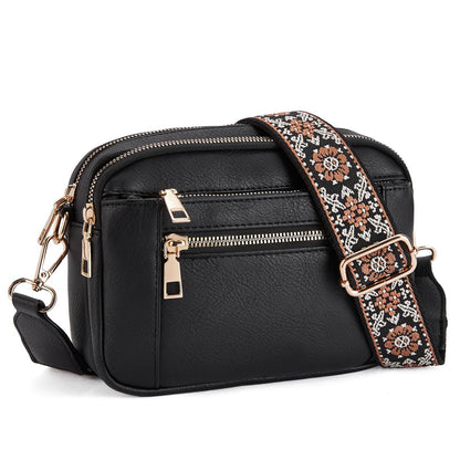 Black crossbody bag with a patterned strap on a white background