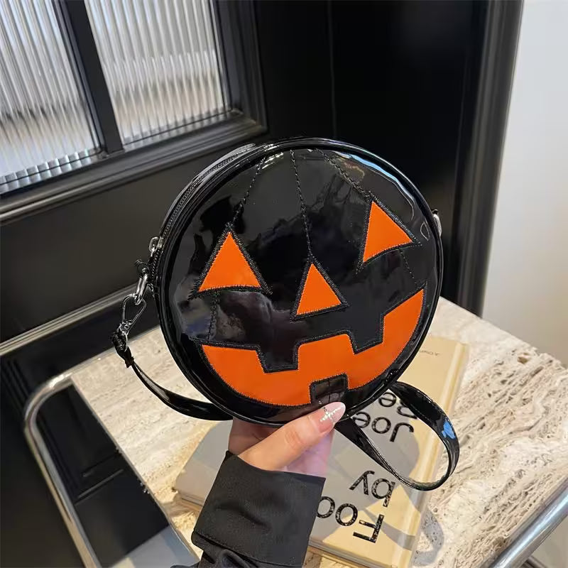 Round black and orange Halloween purse held by a hand indoors.