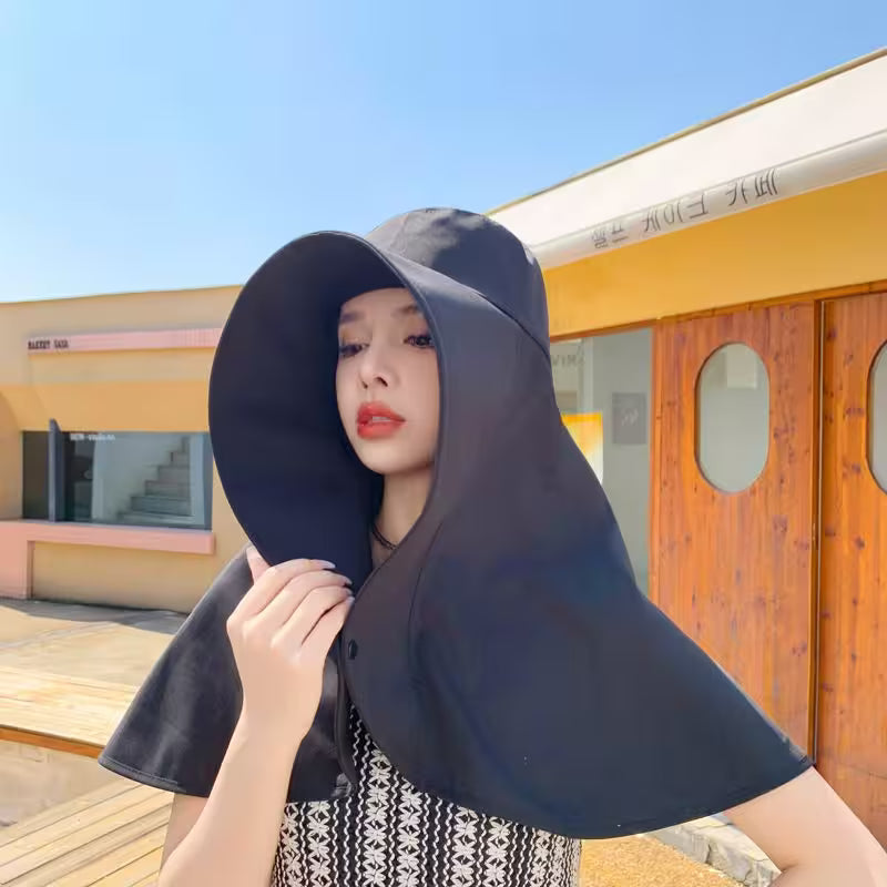 Woman wearing a black hooded cloak outdoors with a colorful building in the background