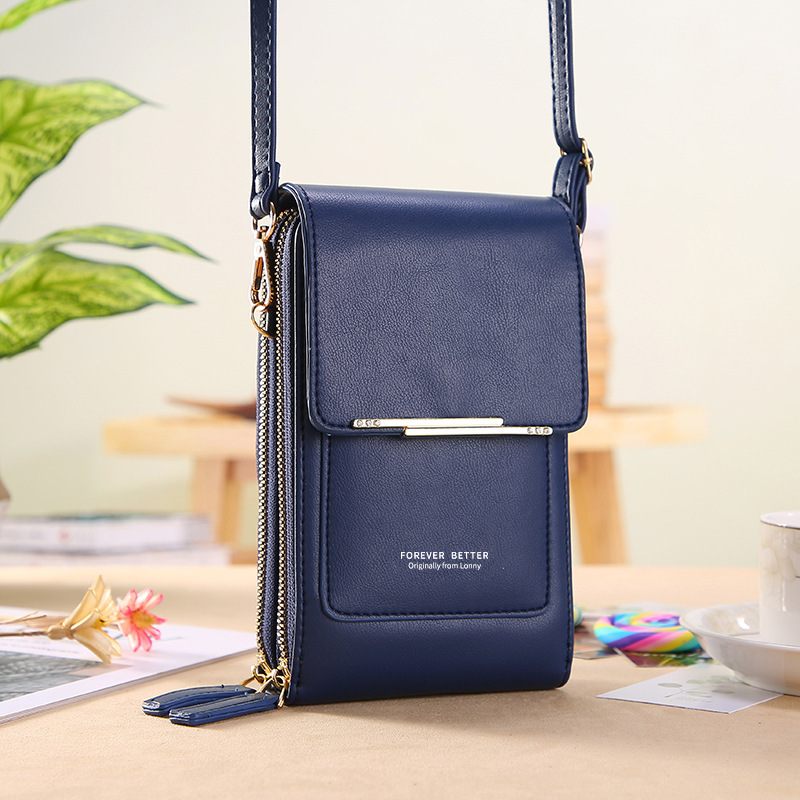 Navy blue crossbody bag on a desk with a blurred background