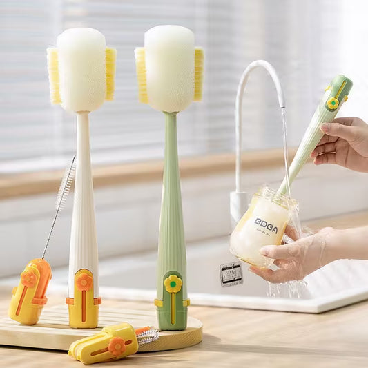 Two kitchen cleaning brushes withstands and a hand holding one, on a light wooden surface.