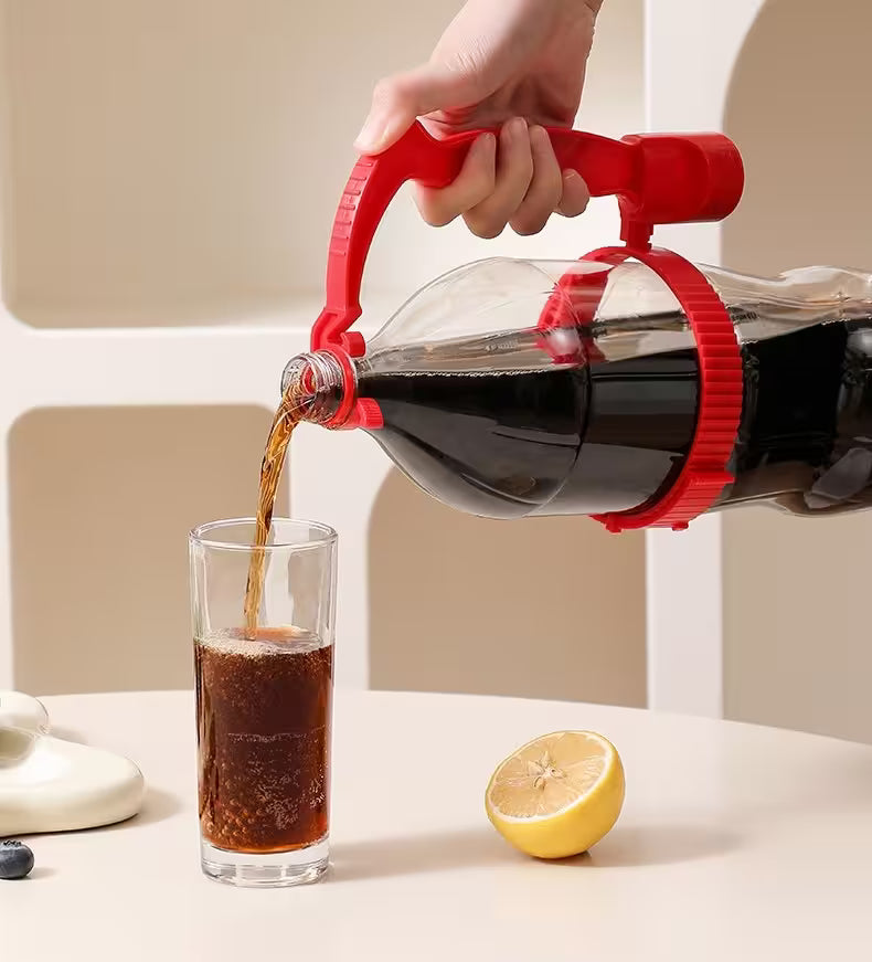 Person pouring dark liquid from a red-handled bottle into a glass with a lemon on a light background