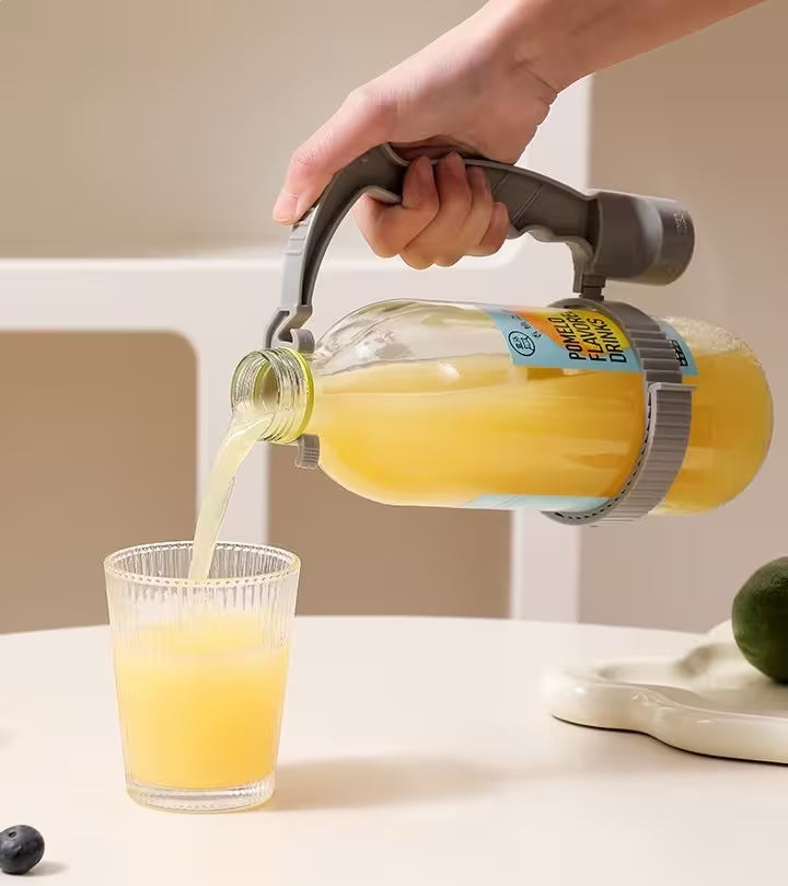 Hand pouring orange juice from a glass bottle into a glass on a light surface.