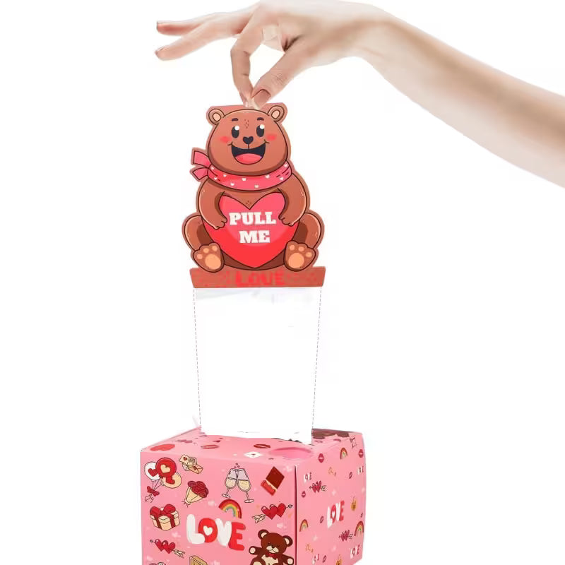 Pink box with a pull tab bear toy, held by a hand on a white background