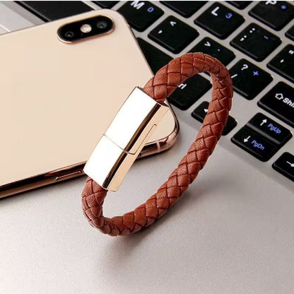 Brown braided USB drive on a laptop keyboard with a gold phone in the background