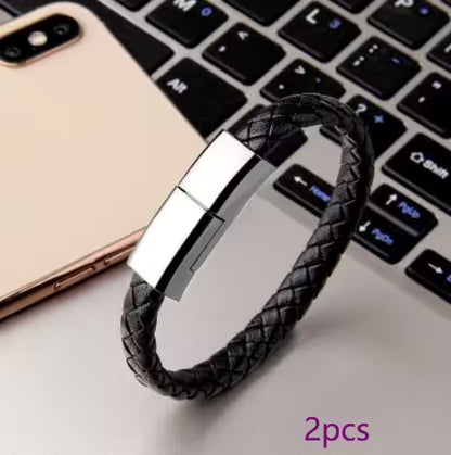 Black braided bracelet with silver tag on a laptop keyboard