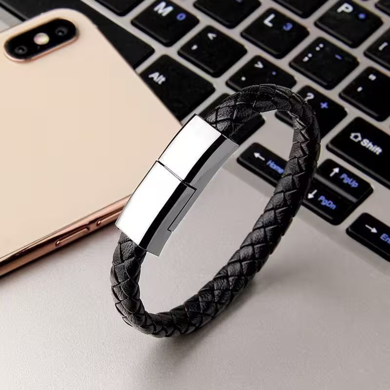 Black braided bracelet with silver clasp on a laptop keyboard