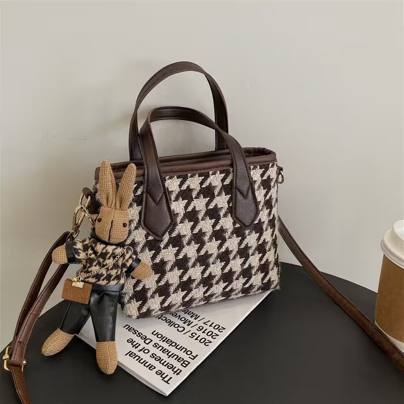 Houndstooth patterned handbag with a rabbit keychain on a surface