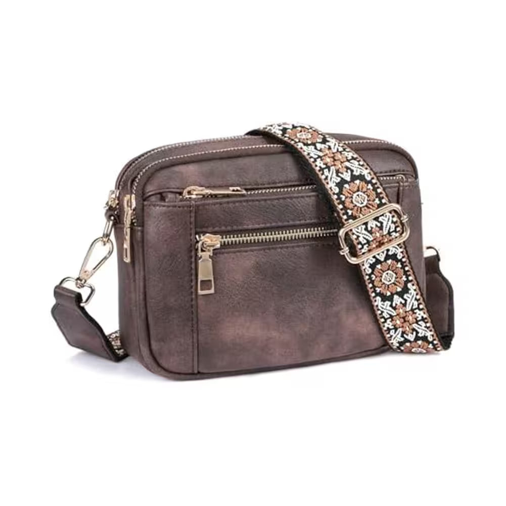 Brown leather crossbody bag with an embroidered strap on a white background