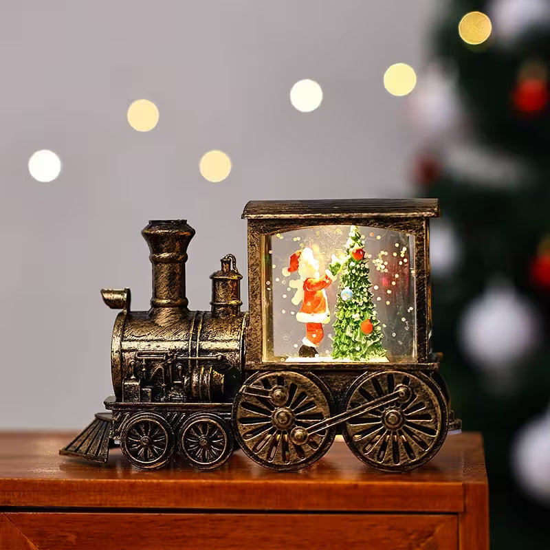 Decorative train with a snow globe featuring a Santa Claus figure and Christmas tree on a wooden surface.
