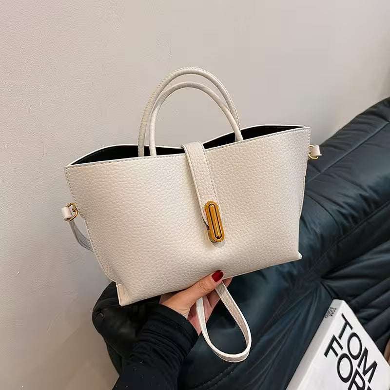 White textured handbag held by a person against a neutral background