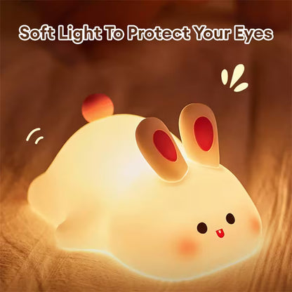 Cute rabbit-shaped night light with a warm glow on a wooden surface.