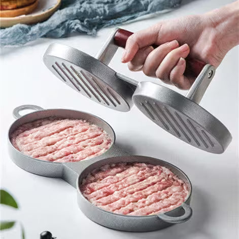 Hamburger press with ground meat on a white surface
